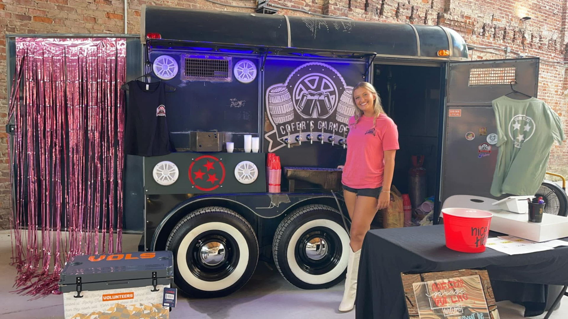 The Cofer's Garage mobile beer trailer with taps, branded barrels, and shirts on display