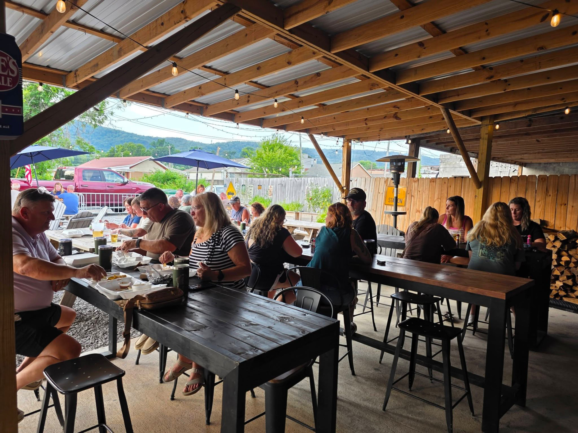 Guests gathered at long wooden tables under the covered garden patio with string lights overhead