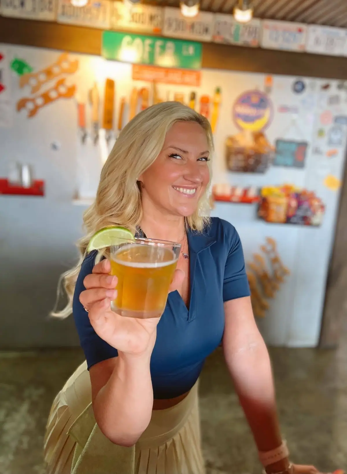 A bartender at Cofer's Garage holding up a beer with a lime wedge in front of the tap wall